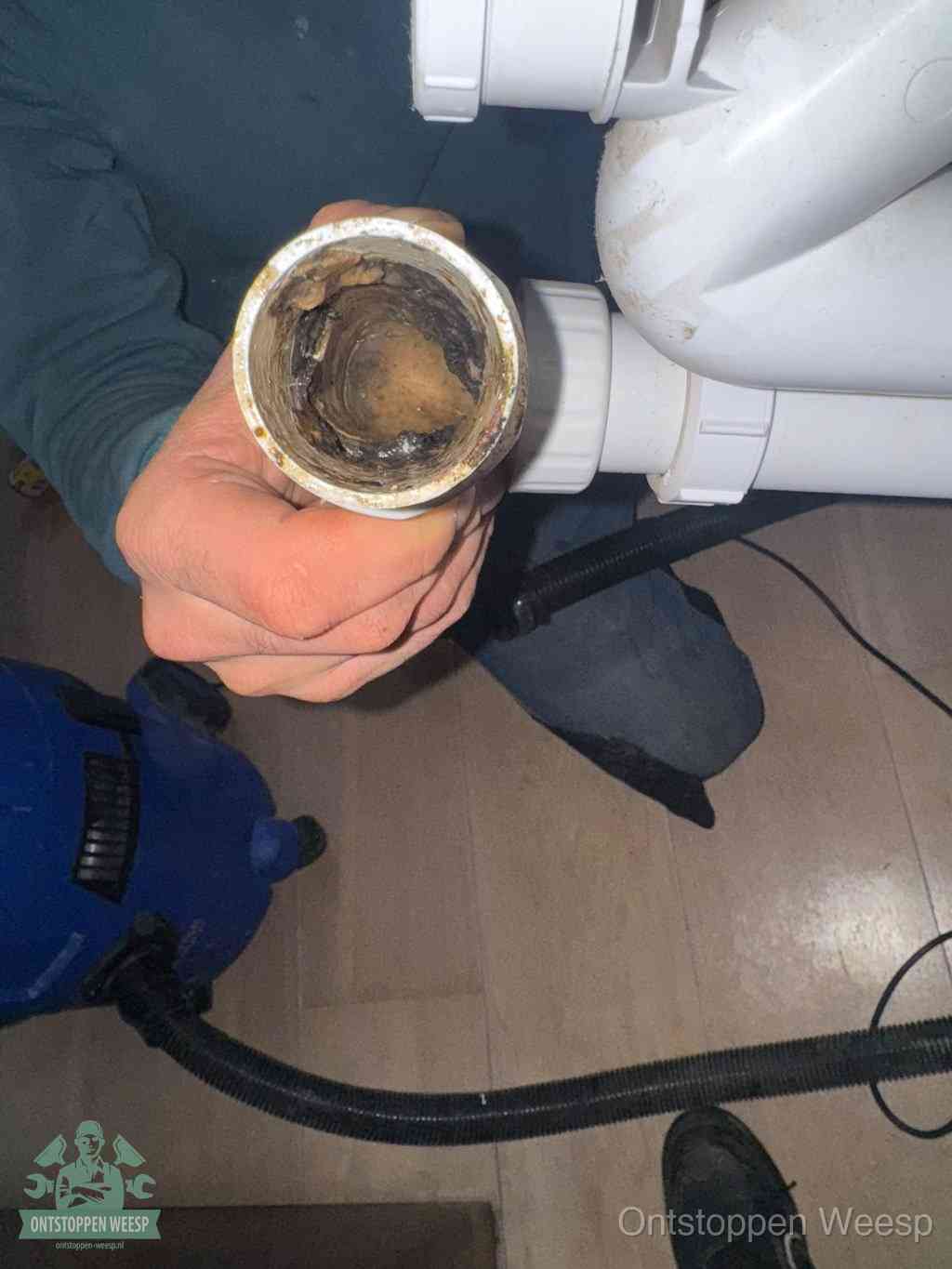 Een losgekoppelde afvoerbuis die van binnen volledig is dichtgeslibd met vet en aanslag, de meest voorkomende oorzaak van een verstopte gootsteen in Weesp