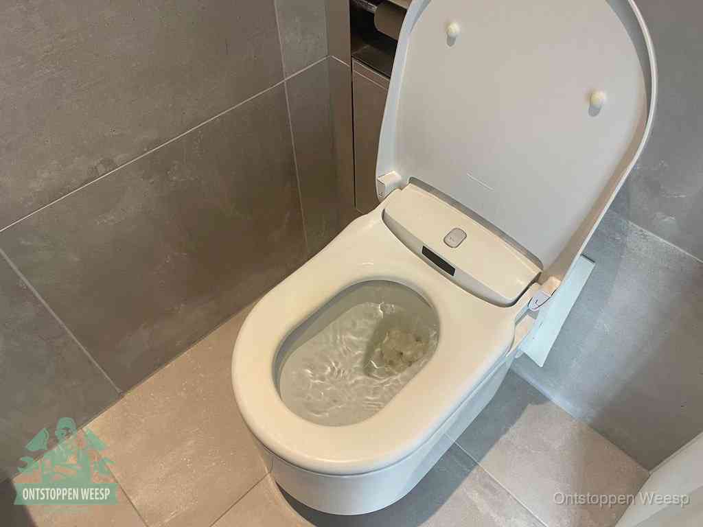 Een toiletpot vol troebel water met drijvend papier en restanten, de meest voorkomende oorzaak van een verstopte wc in Weesp