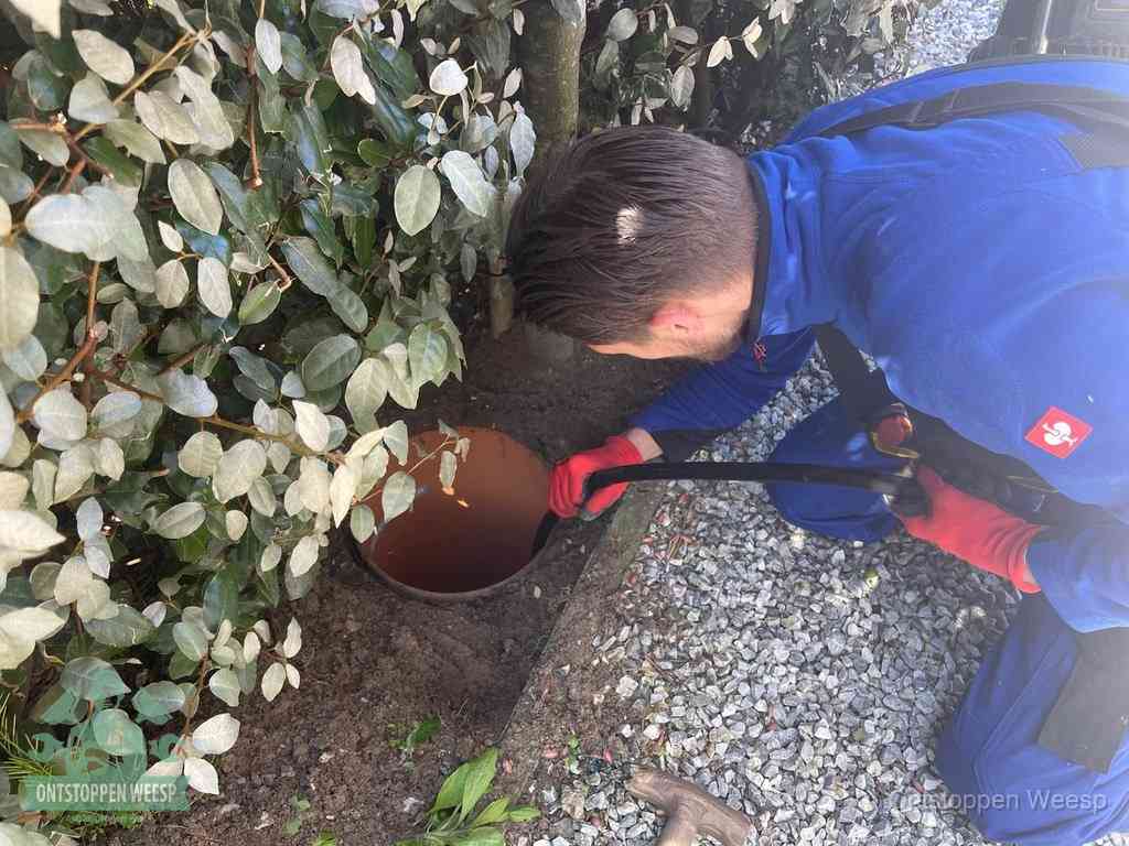 Monteur reinigt een rioolput met een slang, periodieke rioolreiniging in Weesp