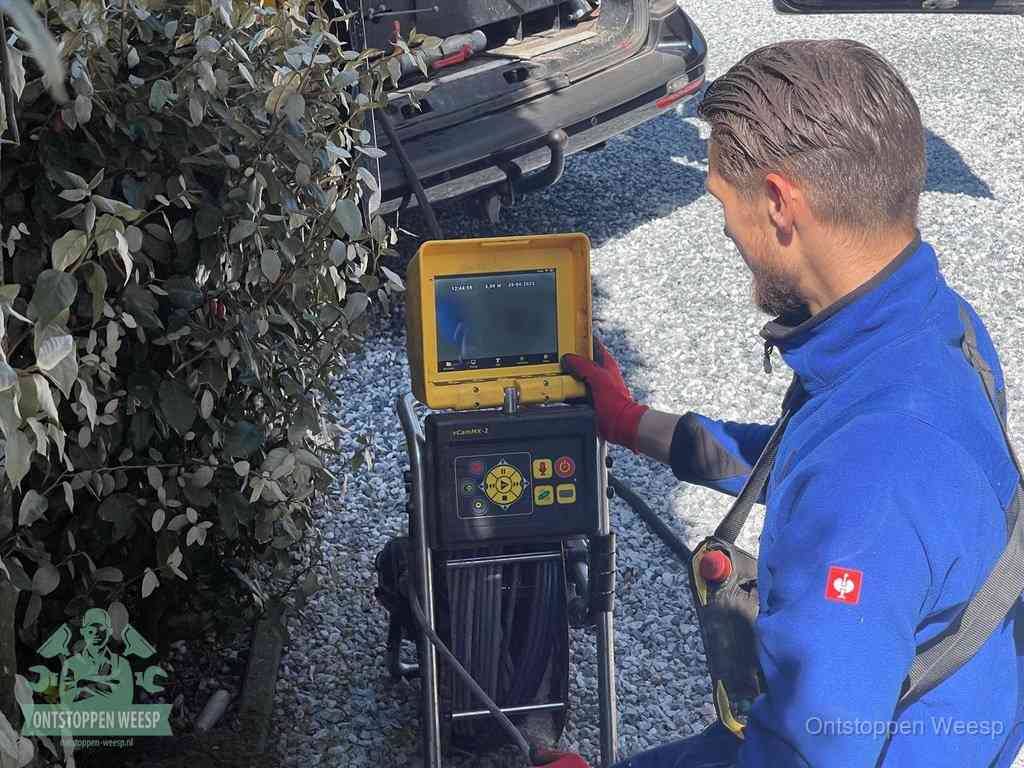 Monteur bedient een rioolinspectiecamera met monitor voor rioolinspectie in Weesp