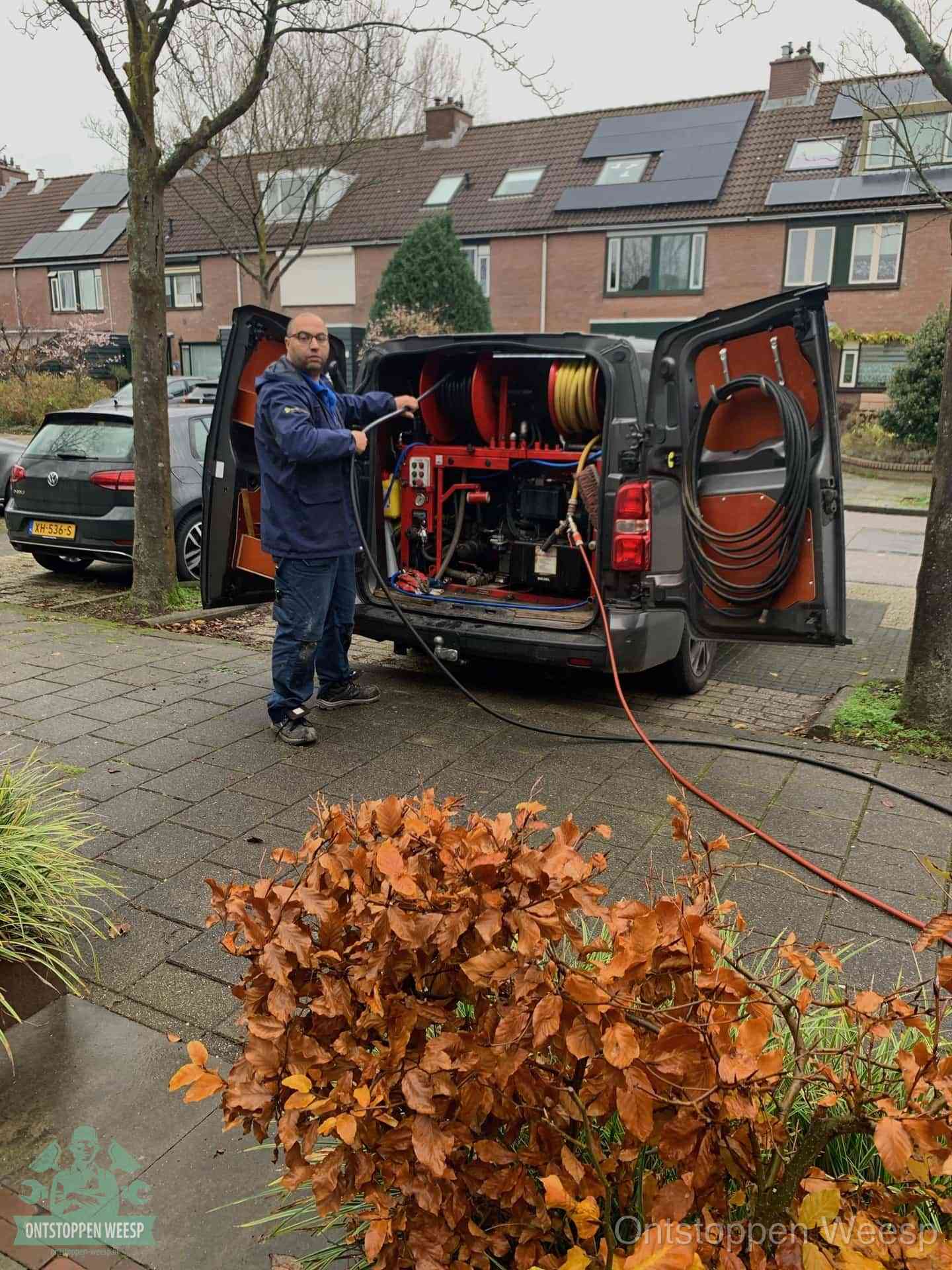 Monteur met rioolreinigingsbus levert rioolservice in de wijk in Weesp
