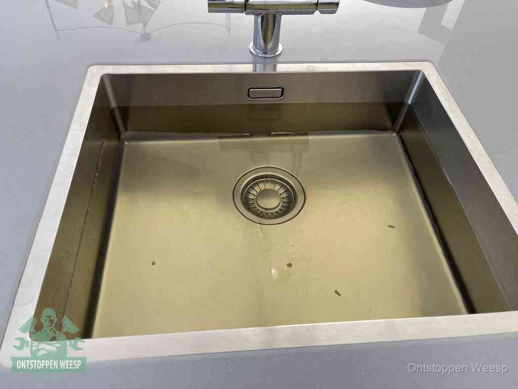 Stilstaand water in een rvs spoelbak dat niet wegloopt, een duidelijk signaal van een gootsteenverstopping in Weesp