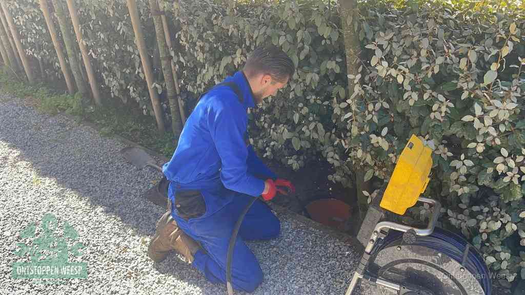 Monteur aan het werk bij een rioolput, de werkwijze voor riool ontstoppen in Weesp