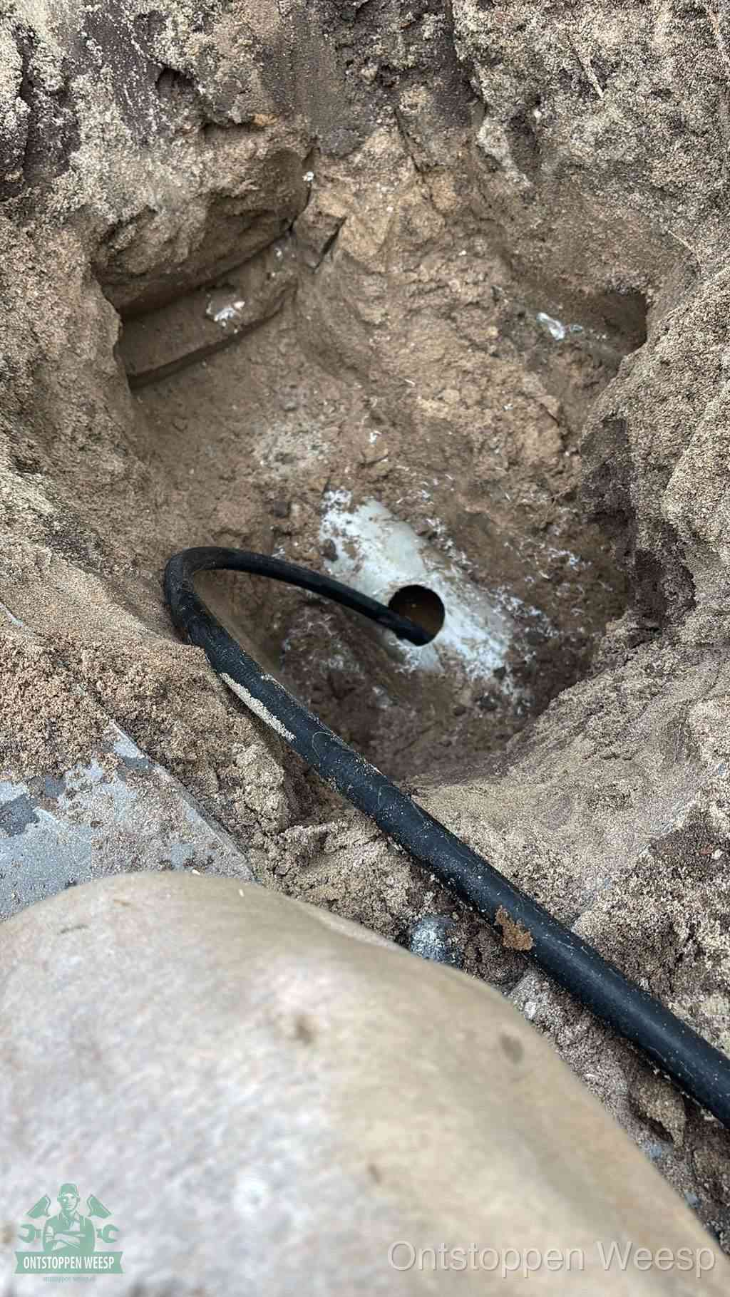 Uitgegraven rioolbuis in de grond, hulp om zelf het riool te ontstoppen in Weesp